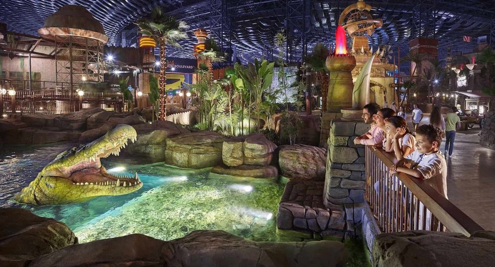Children watching a lifelike crocodile in a themed indoor amusement park at IMG Worlds of Adventure