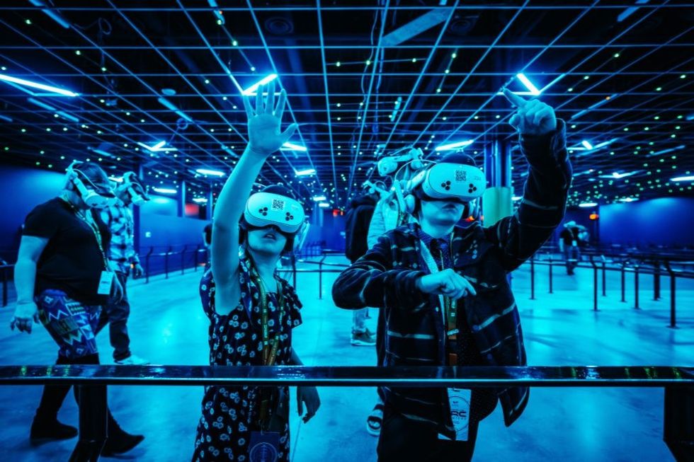 Children wearing VR headsets in a futuristic, blue-lit room with grid ceiling.