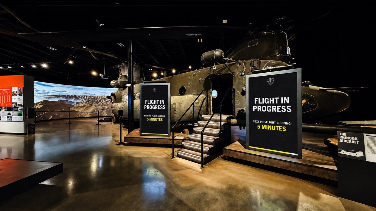 Chinook helicopter in a museum exhibit with "FLIGHT IN PROGRESS" sign.