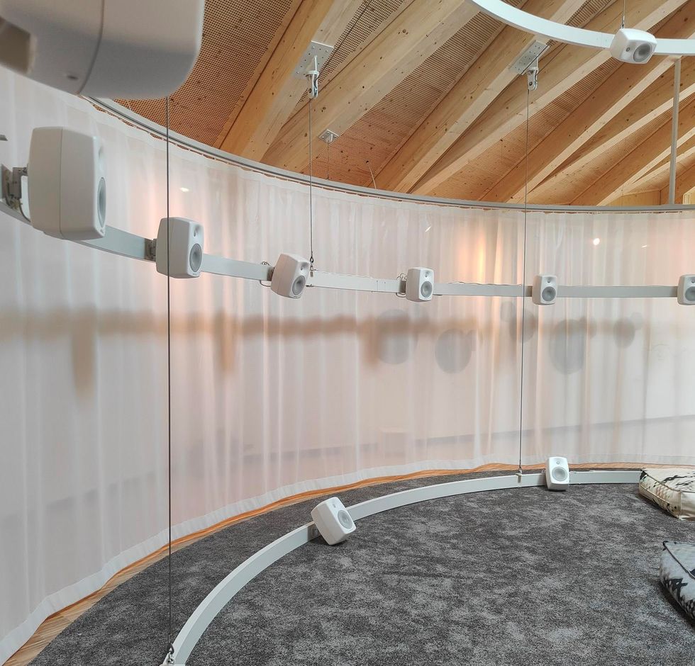 Circular audio setup with white speakers, wood ceiling, and sheer curtains at Klanghaus and Peter Roth Resonance Centre
