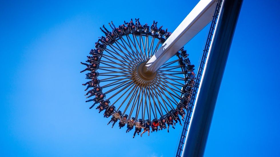 Circular Gyro Swing amusement ride named Aviktas swings high against a clear blue sky.