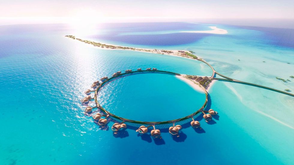 Circular overwater villas on turquoise ocean with a sandy island in the background.