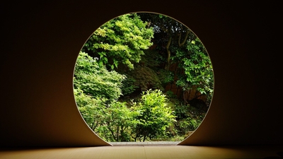 Circular window framing a lush green garden view.