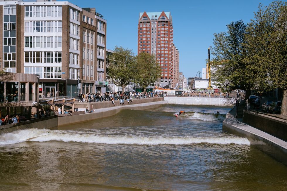 City canal with urban surfing and people gathered on the banks.