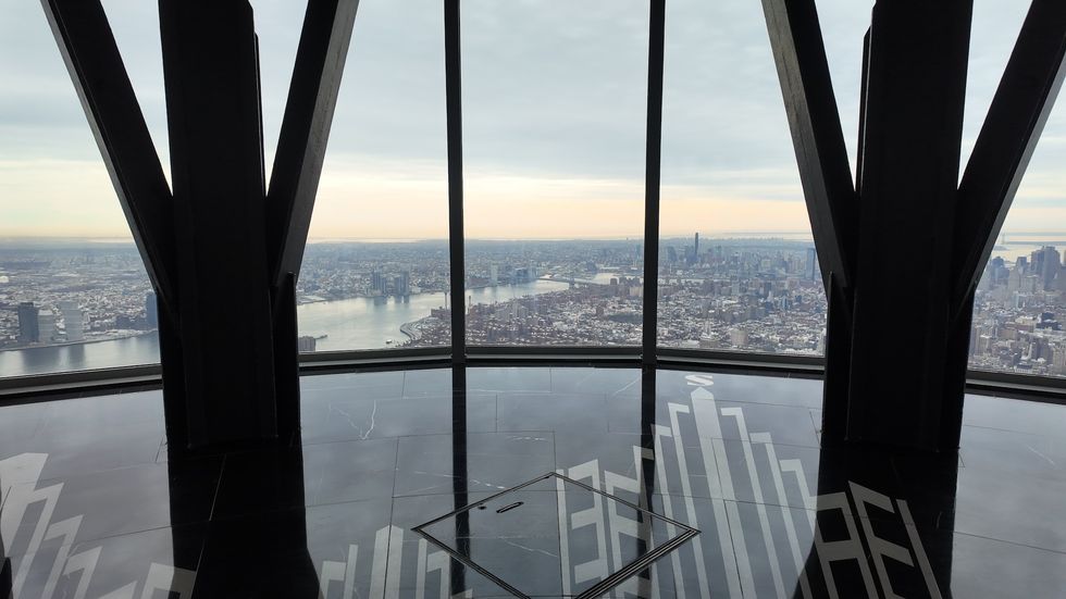 City skyline view from an observation deck with large triangular window frames.