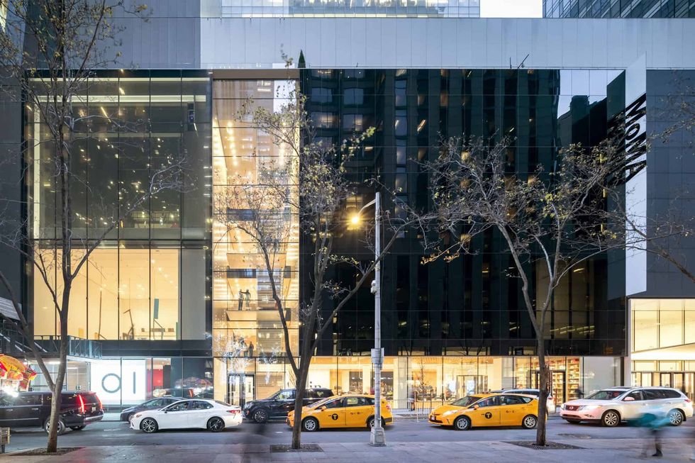 City street view with modern glass building, MoMA and yellow taxis in front.