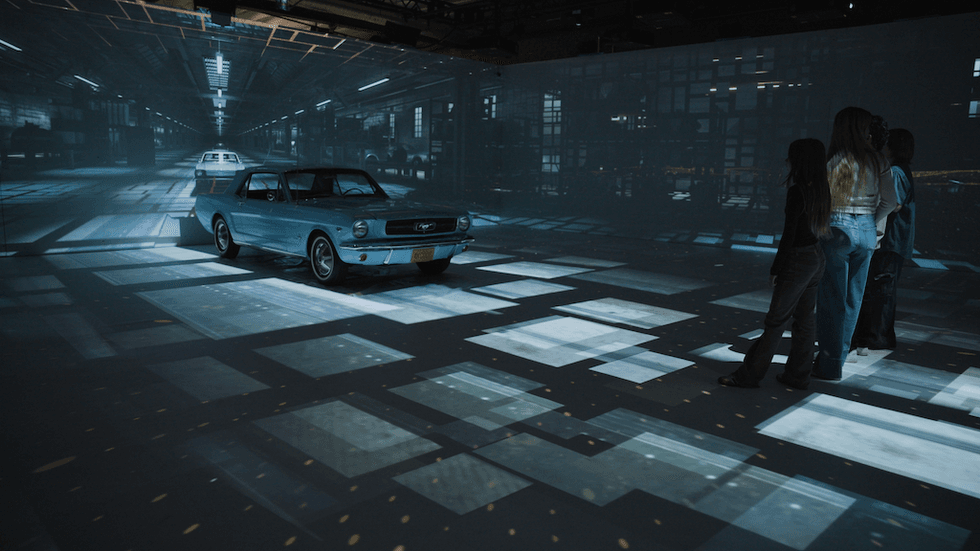 Classic car in a futuristic light display with people observing.