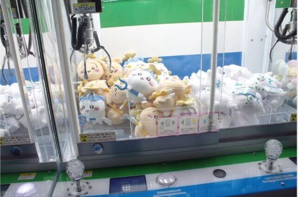 Claw machine filled with colorful, smiling plush toys inside a glass display.