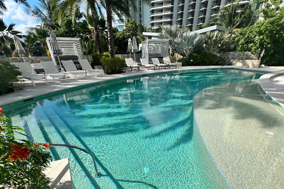 Clear pool with an ozone system, with lounge chairs, surrounded by tropical foliage.