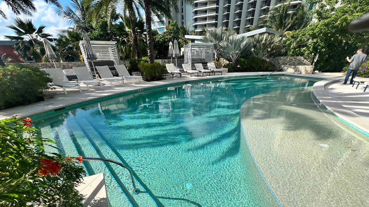 Clear pool with an ozone system, with lounge chairs, surrounded by tropical foliage.