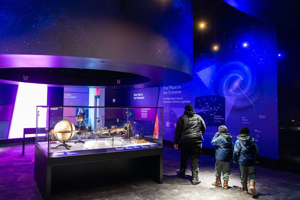Cleveland Museum of Natural History Family exploring a space-themed exhibit with cosmic displays and artifacts.