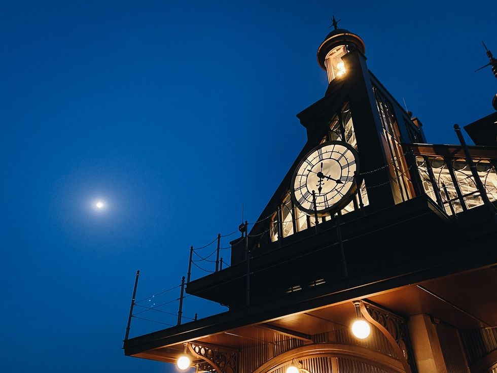 Clock tower at dusk with a bright moon on the left.