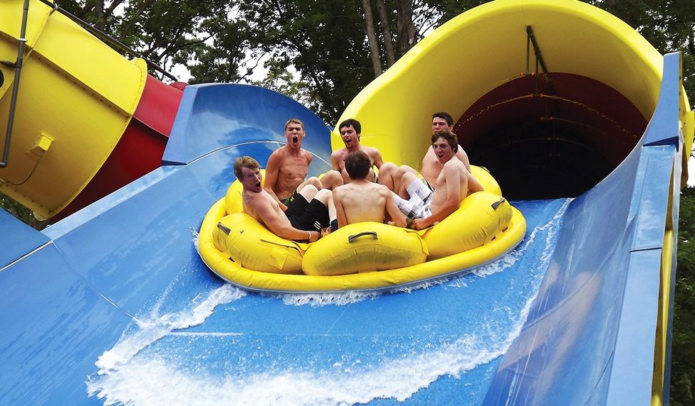 Close-up image of six males on a large raft traveling down hill on a hydro magnetic mammoth water coasters