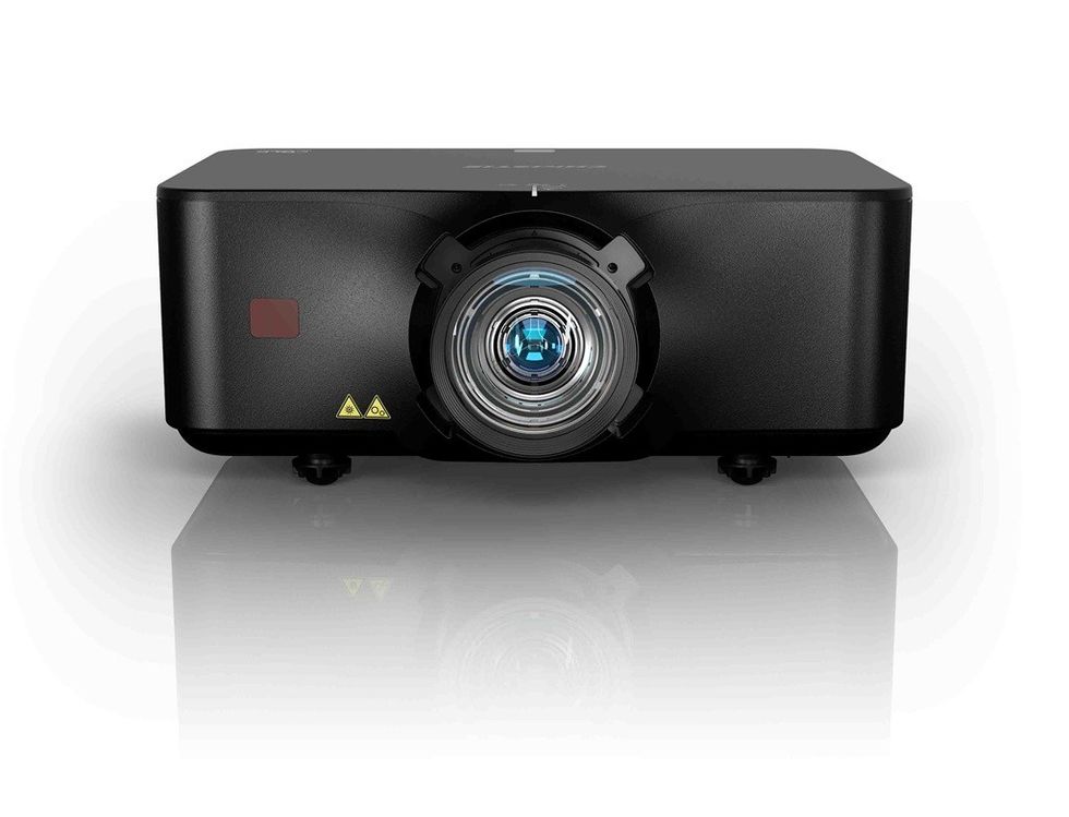 Close-up of a black projector with illuminated lens on a reflective surface.