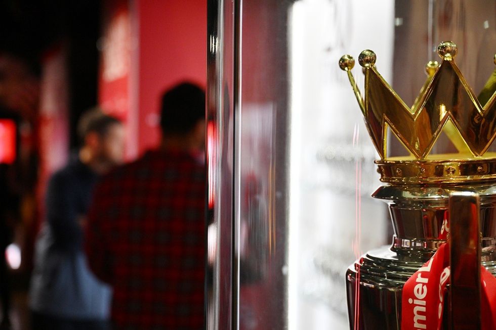 Close-up of a trophy crown in a glass case with blurred people in the background.