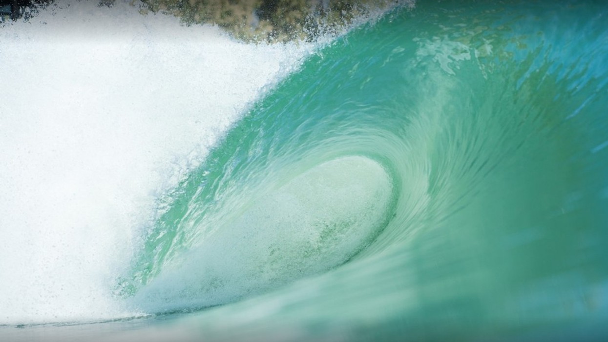 Close-up of a turquoise ocean wave forming a tube with white frothy spray.