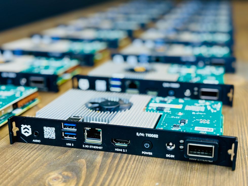 Close-up of computer circuit boards with various ports on a wooden surface.
