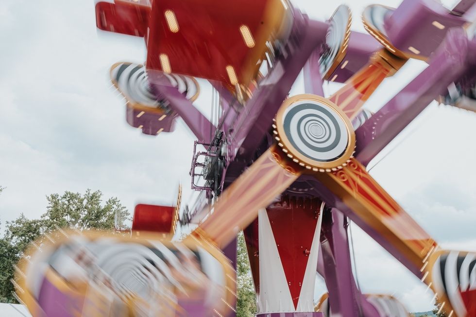 Colorful amusement park ride in motion, spinning fast against a cloudy sky.