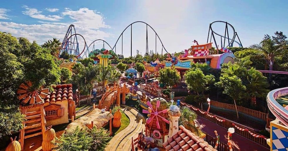 Colorful amusement park with rides, trees, and a roller coaster in the background.