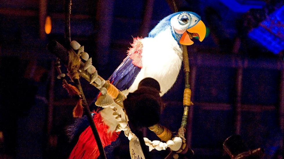 Colorful animatronic parrot on a swing against a dark background, Enchanted Tiki Room attraction, Disneyland