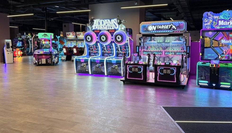 Colorful arcade with various illuminated game machines and attractions.