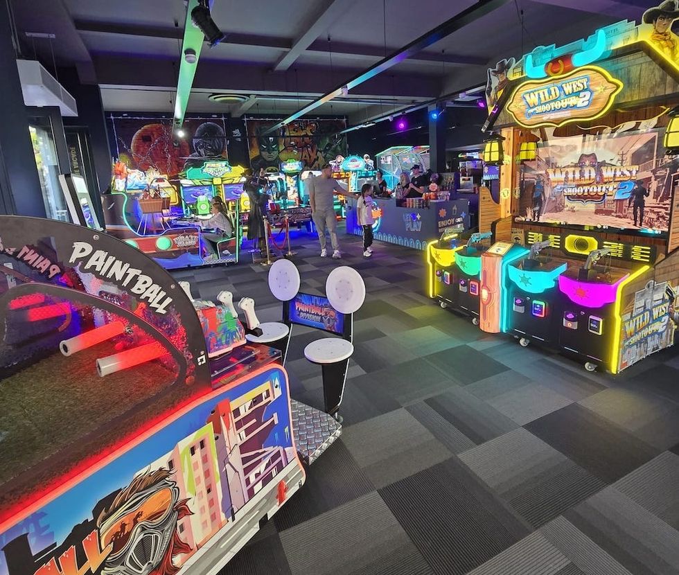 Colorful arcade with video games and a paintball shooting game.