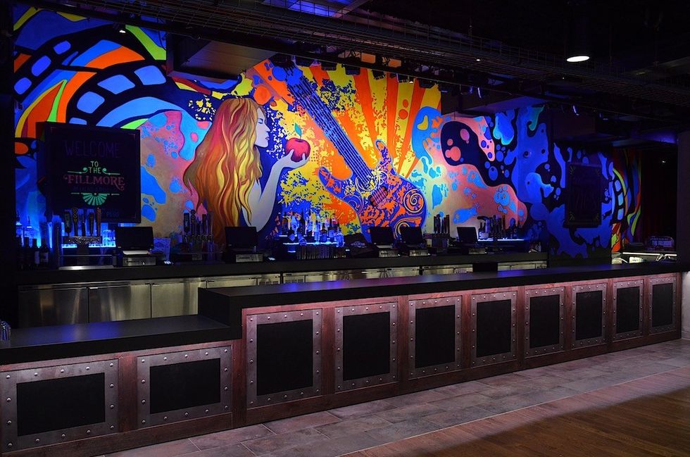 Colorful bar mural with a woman holding an apple and a large, intricate guitar design.