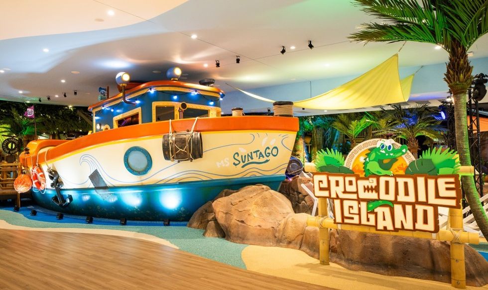 Colorful boat and "Crocodile Island" sign in a tropical-themed indoor setting.