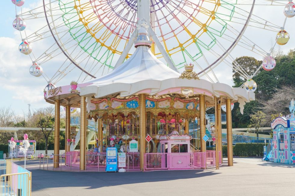 Colorful carousel and Ferris wheel at an amusement park under a blue sky.