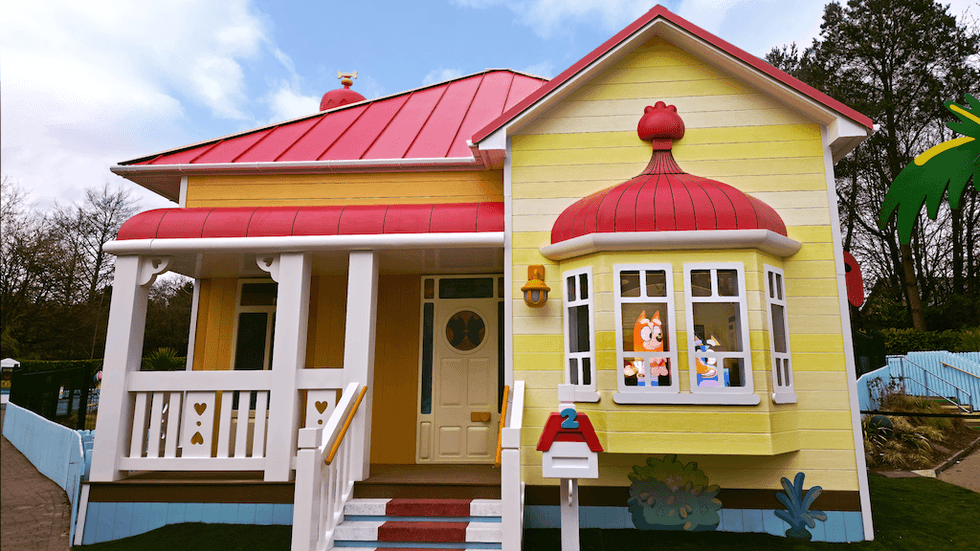 Colorful cartoon-themed yellow house with red roof and fun decorations.
