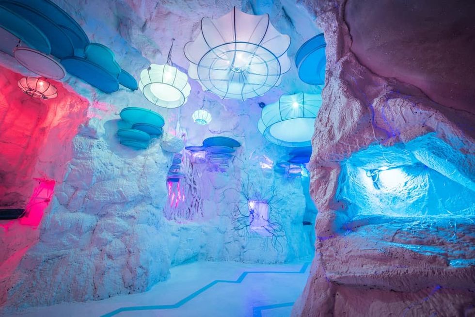 Colorful cave interior with whimsical ceiling lights and textured rock formations.