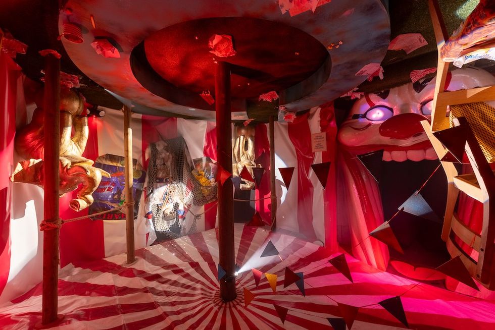 Colorful circus-themed room with red and white stripes, large clown face, and trapeze decor.