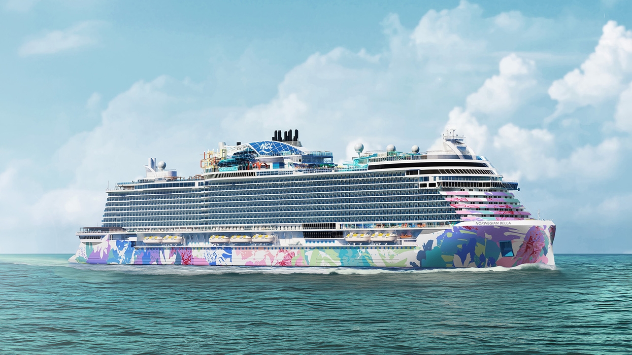 Colorful cruise ship sailing on a calm ocean under a blue sky with clouds.