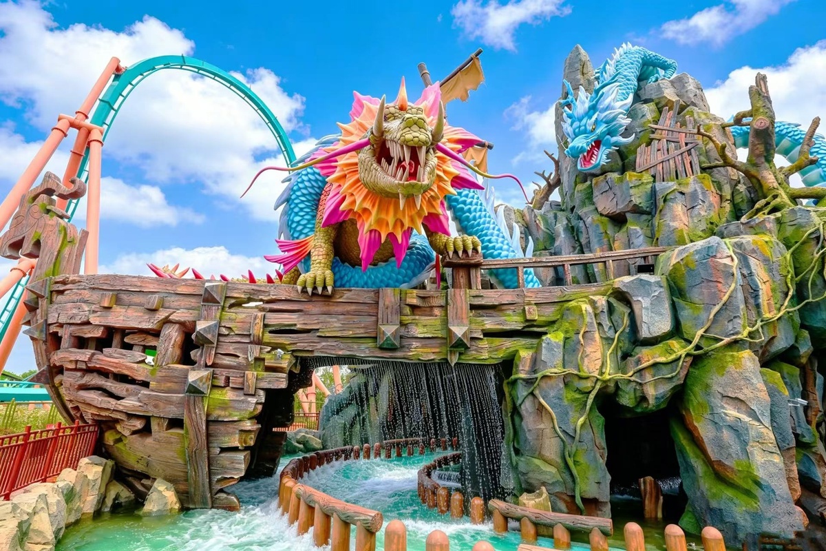Colorful dragon sculpture adorns a theme park ride at Xiaogan Fantawild Resort with water below.