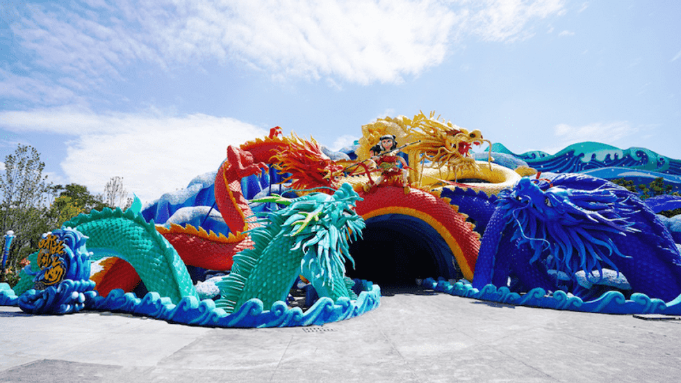 Colorful dragon sculptures with a figure on top under a bright blue sky at Mianyang Fantawild Oriental Heritage Park