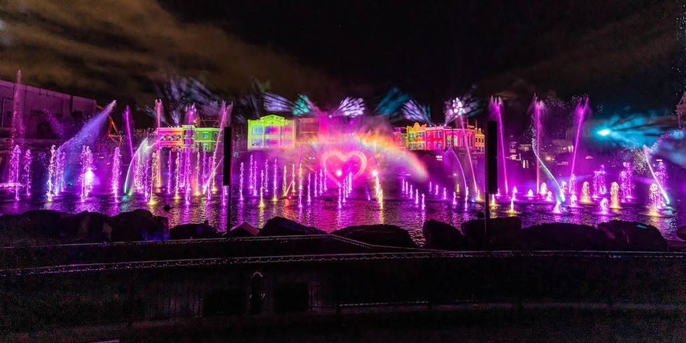 Colorful fountain show with heart-shaped lights at night.