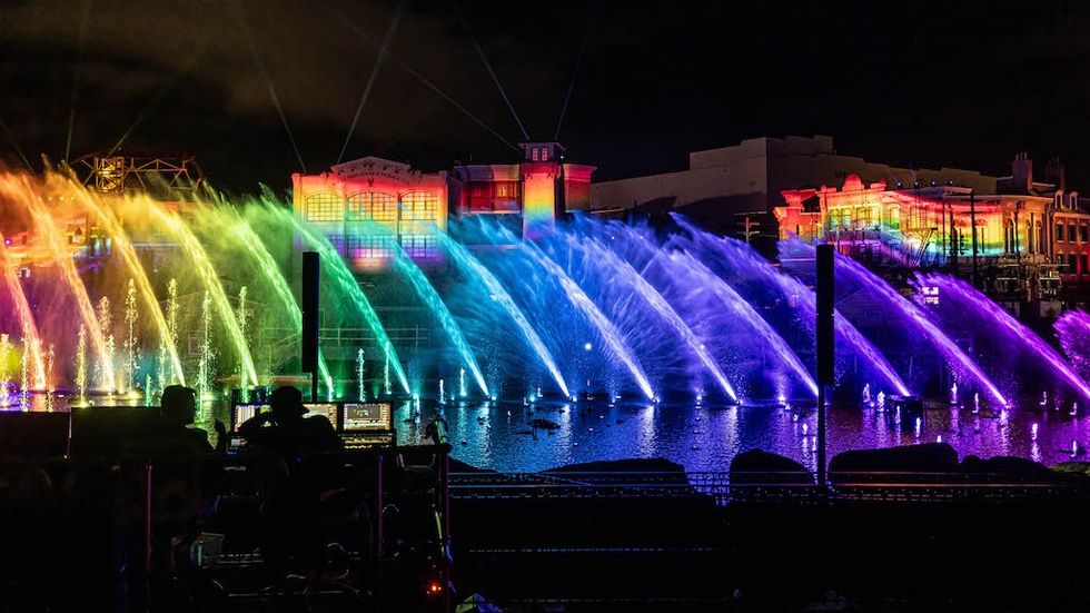 Colorful fountains and buildings illuminated with rainbow lights at night.