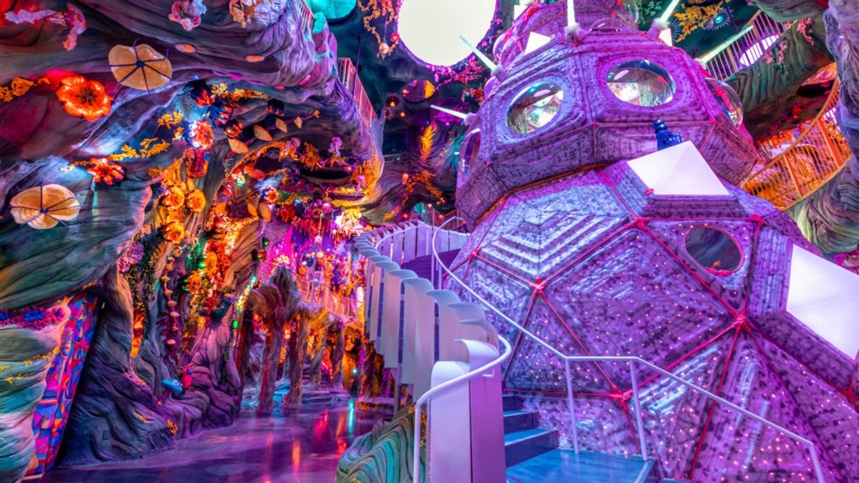 Colorful, futuristic indoor exhibit with vibrant lights, plants, and geometric structures - Meow Wolf's Convergence Station, Denver