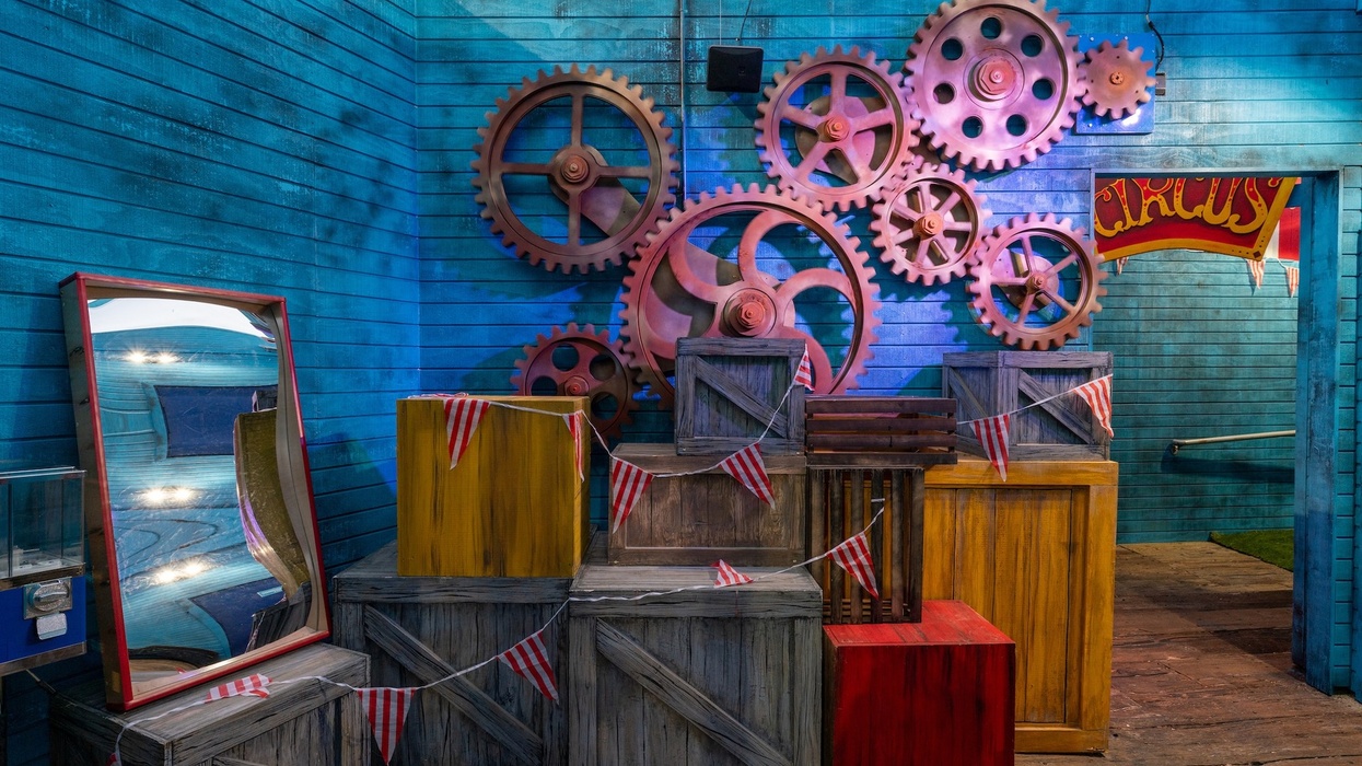 Colorful gears and crates with a circus theme against a blue wooden wall.