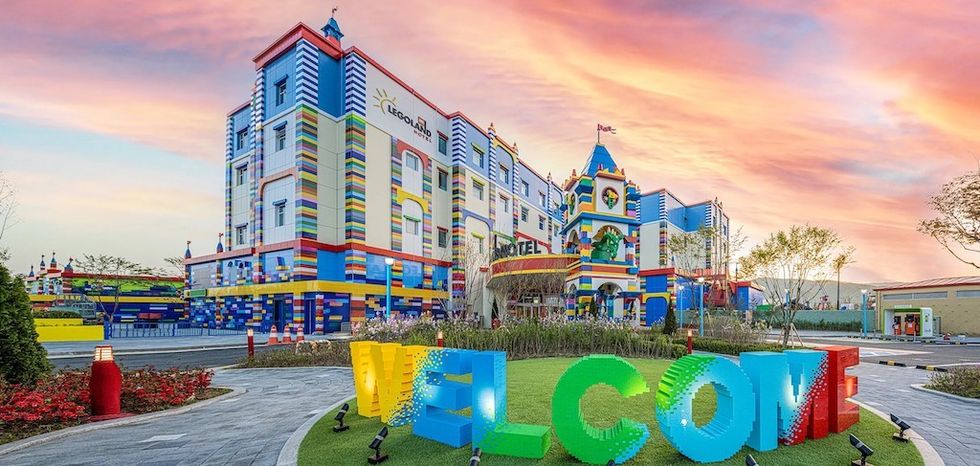 Colorful hotel with LEGO-like design and "WELCOME" sign at sunset.