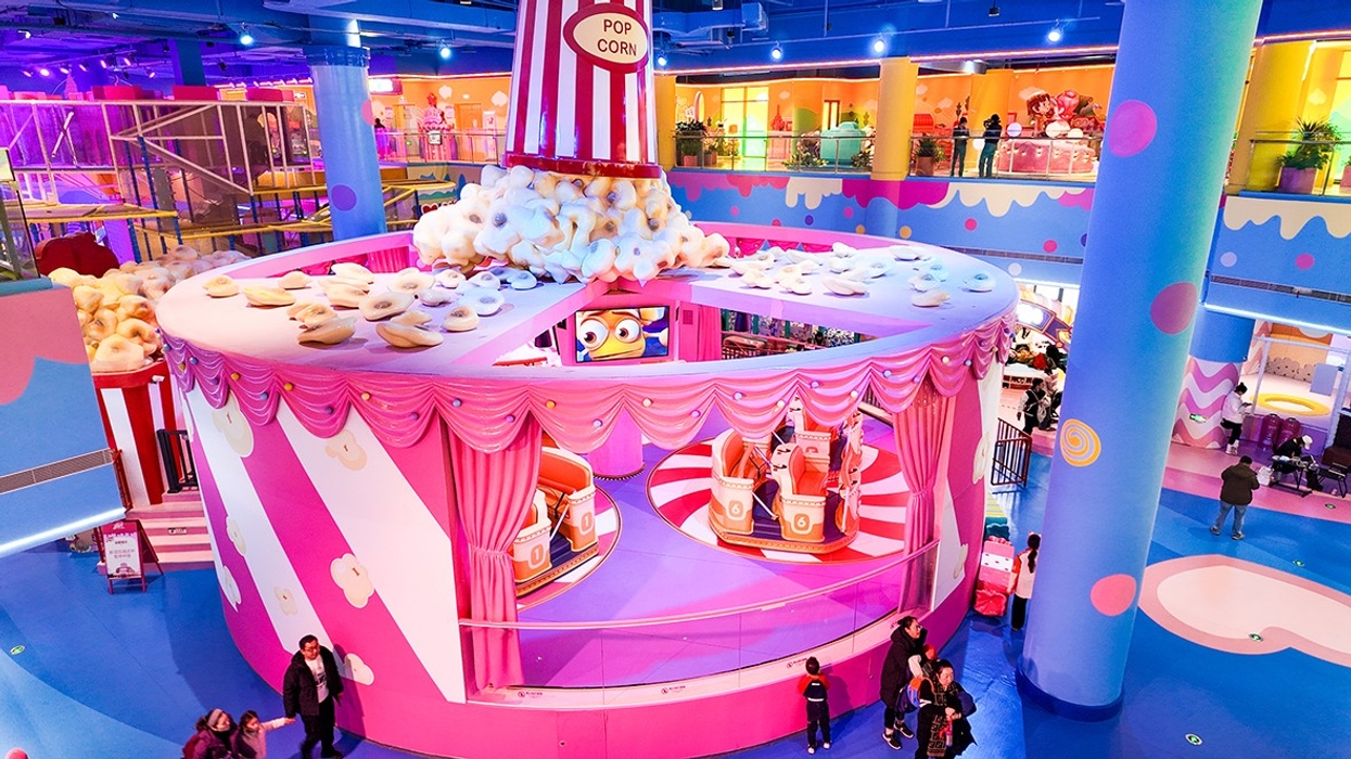 Colorful indoor amusement park with a popcorn-themed attraction and visitors walking around.