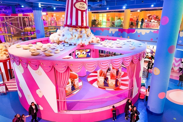 Colorful indoor amusement park with a popcorn-themed attraction and visitors walking around.