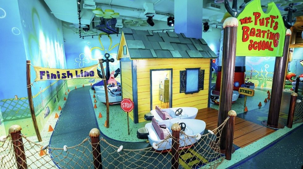 Colorful indoor boating school with track, boats, and cartoon decor.