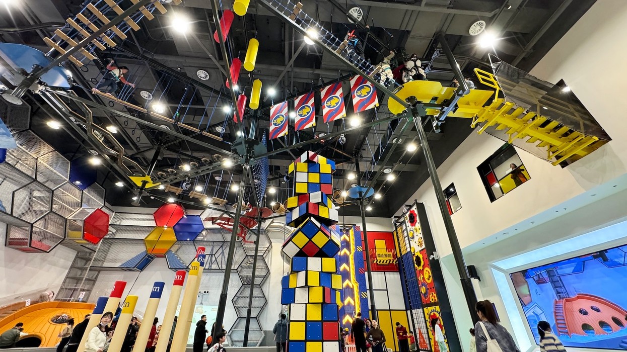 Colorful indoor playground with climbing structures and suspended platforms.