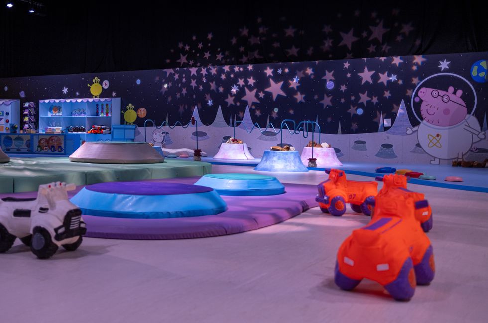 Colorful indoor playground with space-themed decor and toy vehicles.