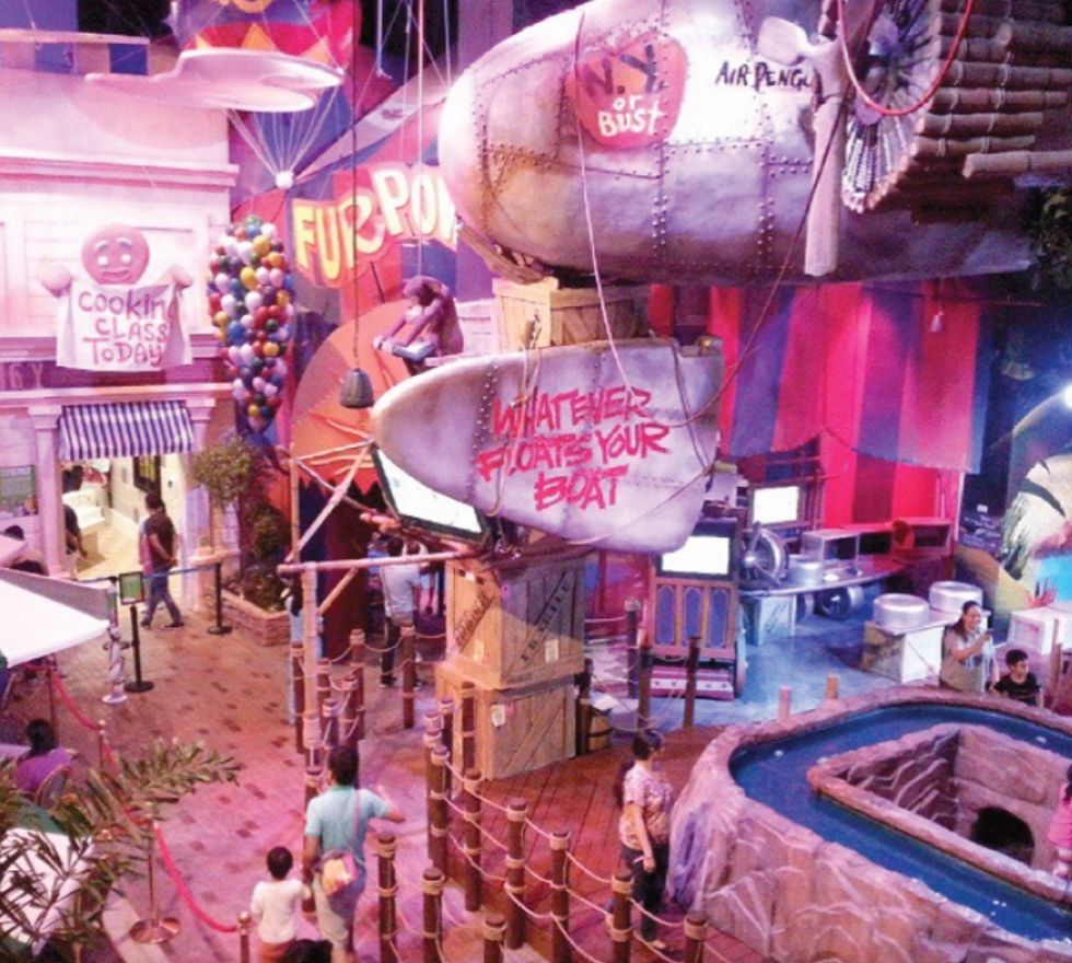 Colorful indoor theme park with whimsical decorations and a water ride.