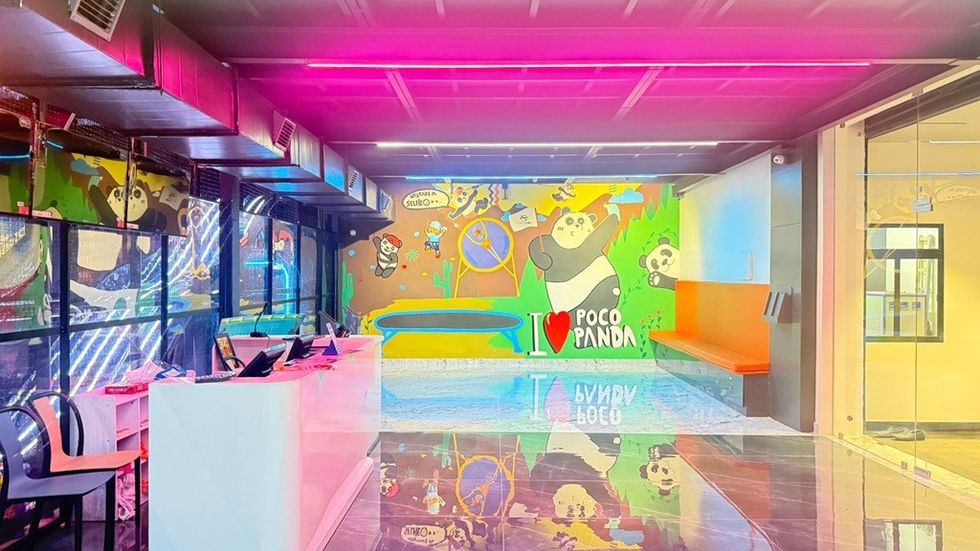 Colorful interior with panda-themed murals, neon lights, and a modern white counter.