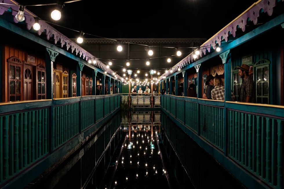 Colorful, lantern-lit walkway with reflections and people gathered at the end.