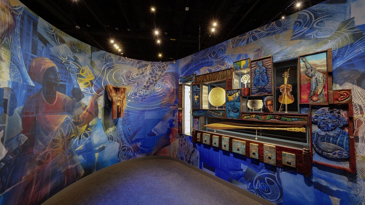 Colorful museum exhibit with murals, cultural artifacts, and vibrant lighting.