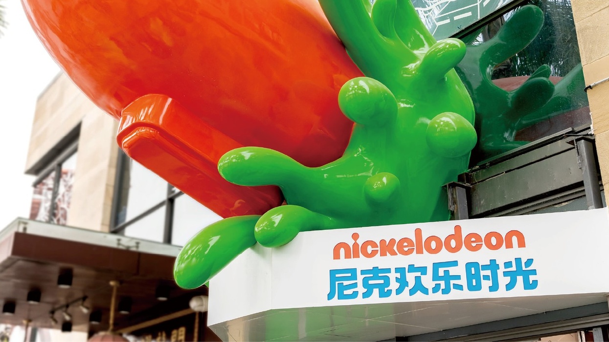 Colorful Nickelodeon sign with orange and green splatter design on building exterior.